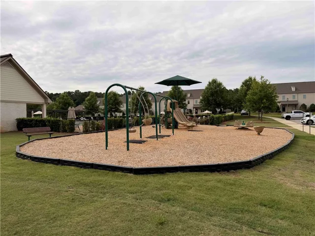 A well-maintained community playground with a wood chip surface, next to the pool, and ready for recreation.