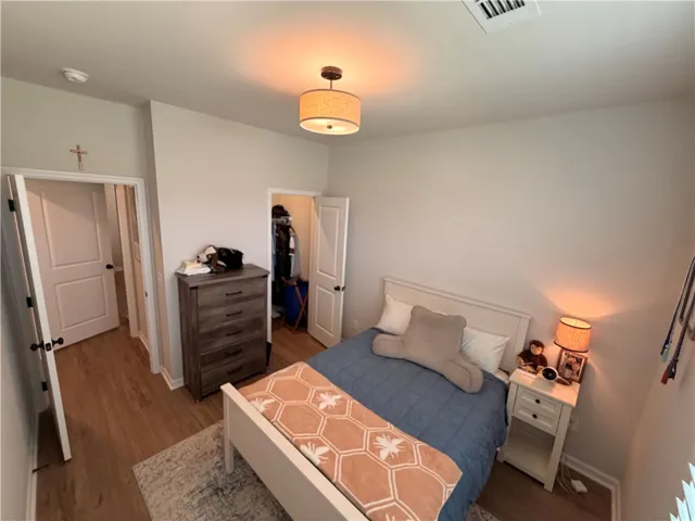Bedroom 3. Comfortable bedroom featuring warm lighting, LVP flooring, WI lit closet, and plantation shutter treatments.
