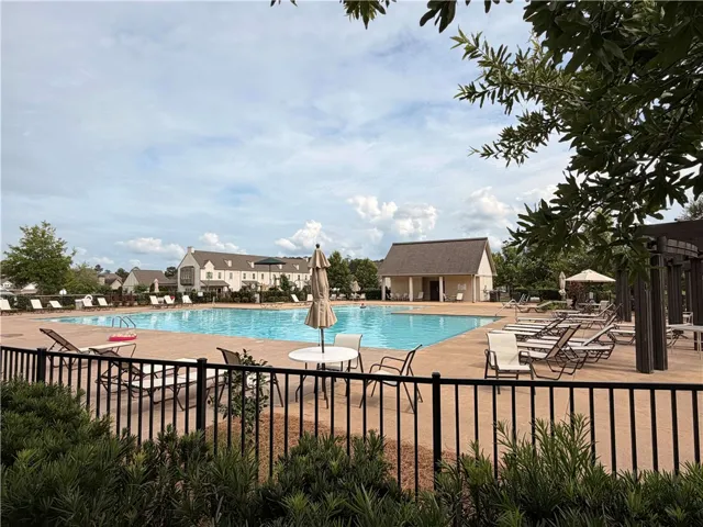 A spacious community pool area awaits, surrounded by lounge seating and a convenient pool house.