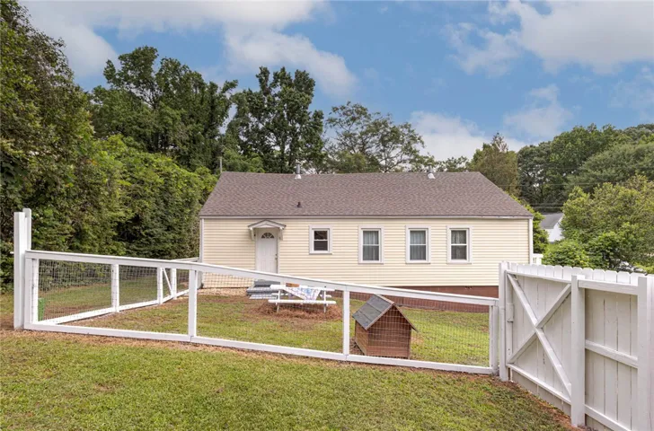 A fenced private yard surrounds this welcoming single-story home, nestled among mature trees.