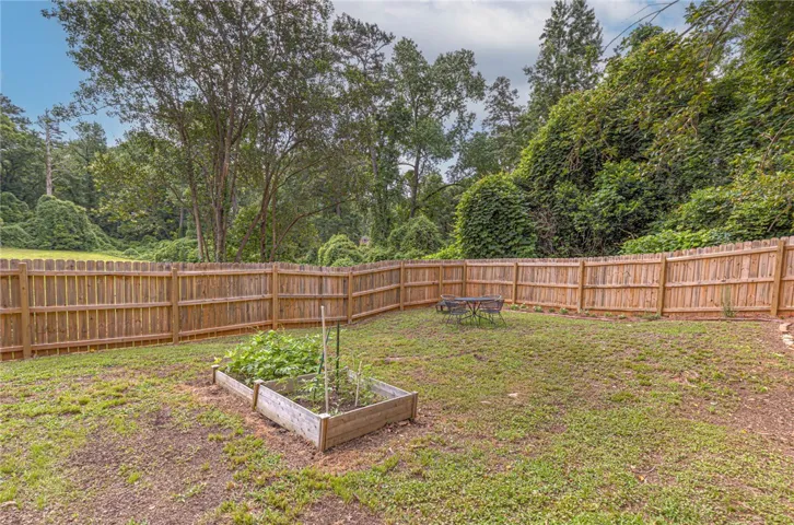 A wooden privacy fence encloses a green lawn, complete with a raised garden bed and ample space for outdoor enjoyment.