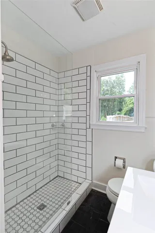 Modern shower design with subway tile walls and hexagon tile floor offers a clean, contemporary bathing experience.