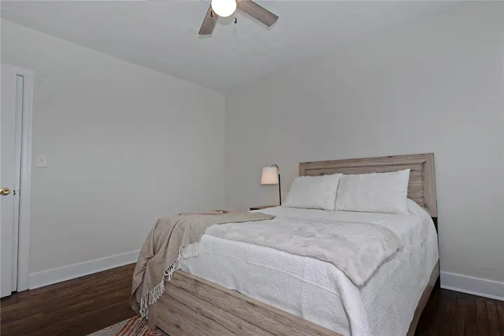 An inviting bedroom features rich hardwood flooring and a functional ceiling fan for comfort.