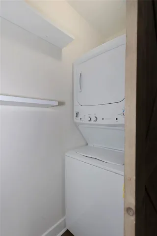 A compact laundry space features a stacked washer/dryer unit and convenient wall-mounted shelving.