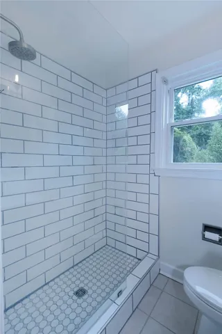 A well-lit shower features classic subway tile walls and a stylish tiled floor.