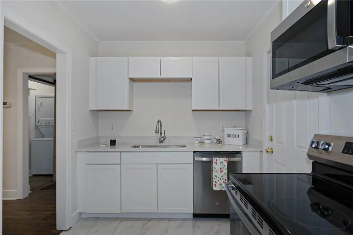 A well-appointed kitchen features white cabinetry and sleek stainless steel appliances, creating a pristine culinary workspace.