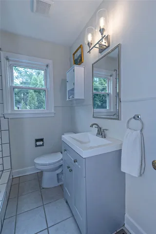 A well-appointed bathroom features a contemporary vanity, large mirror, and tiled floors.