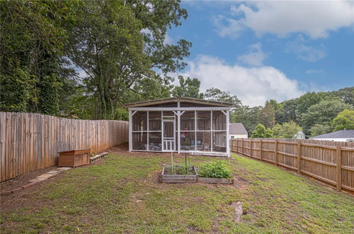 A private, fenced backyard offers a screened-in porch and raised garden beds, perfect for outdoor living.