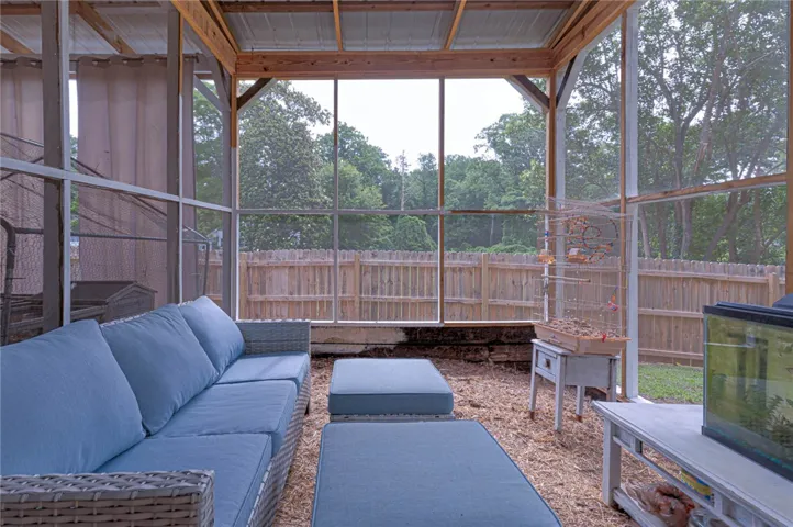 A private backyard oasis with a fenced perimeter and mature trees beyond the screened enclosure.