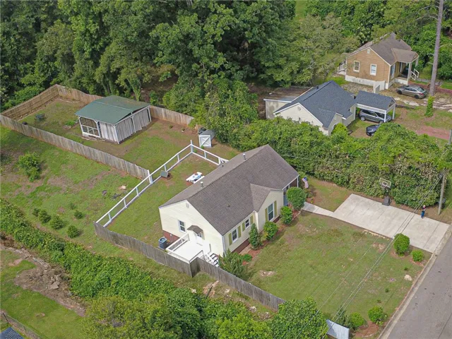An aerial perspective showcases a charming residence with a broad concrete driveway. This is the entire parcel