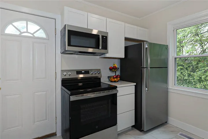 A well-lit kitchen with modern stainless steel appliances and ample cabinetry.