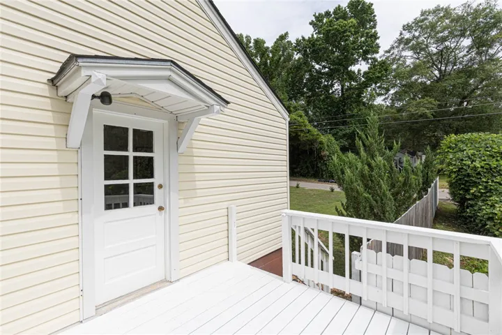 A side deck entrance features a white door with windows, sheltered by a small awning. Access to a side deck from bedroom 3.