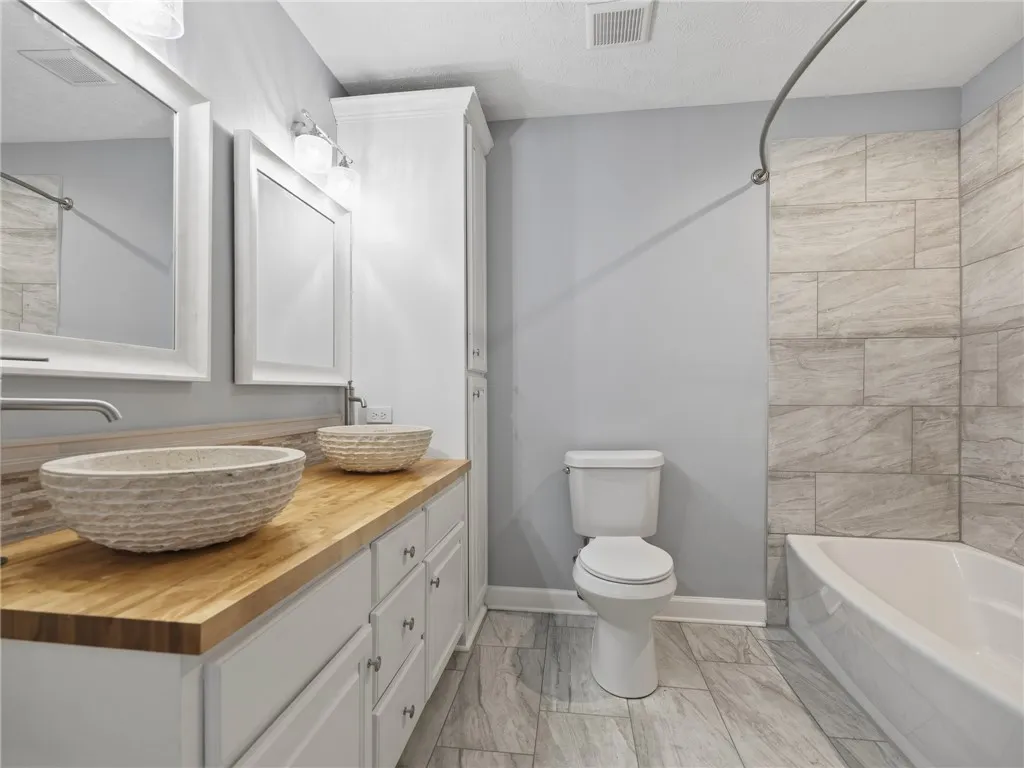 Double vessel sinks and a wood countertop elevate this clean, modern bathroom.