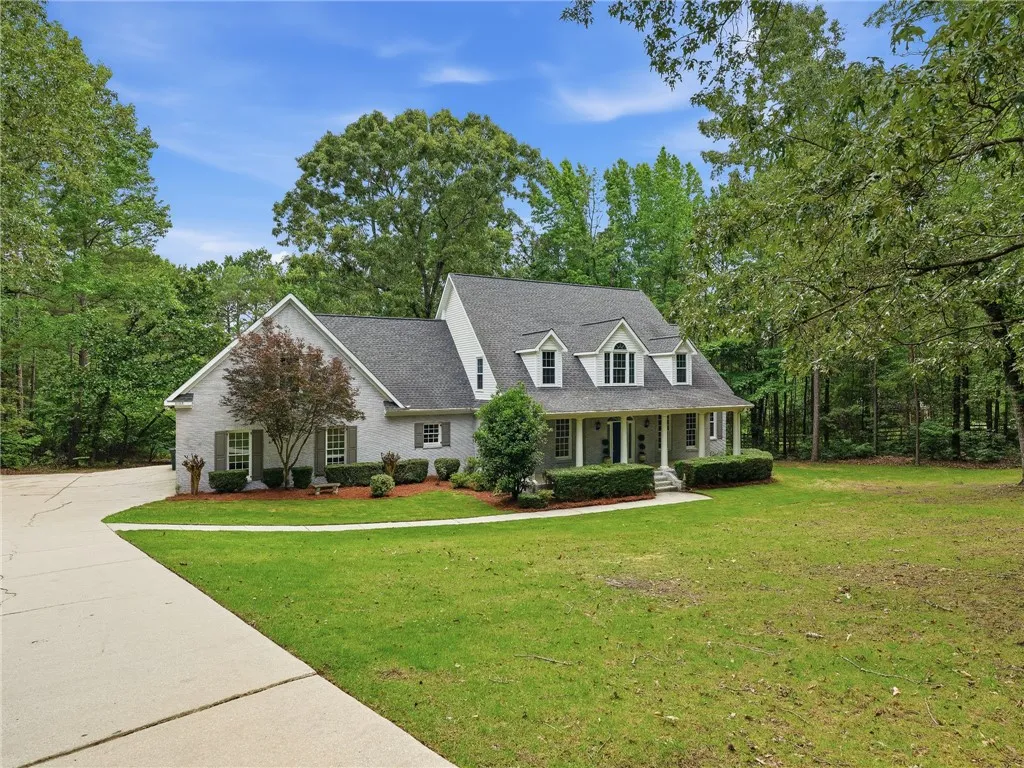 Mature trees frame a classic brick and siding exterior featuring dormer windows and a front porch.