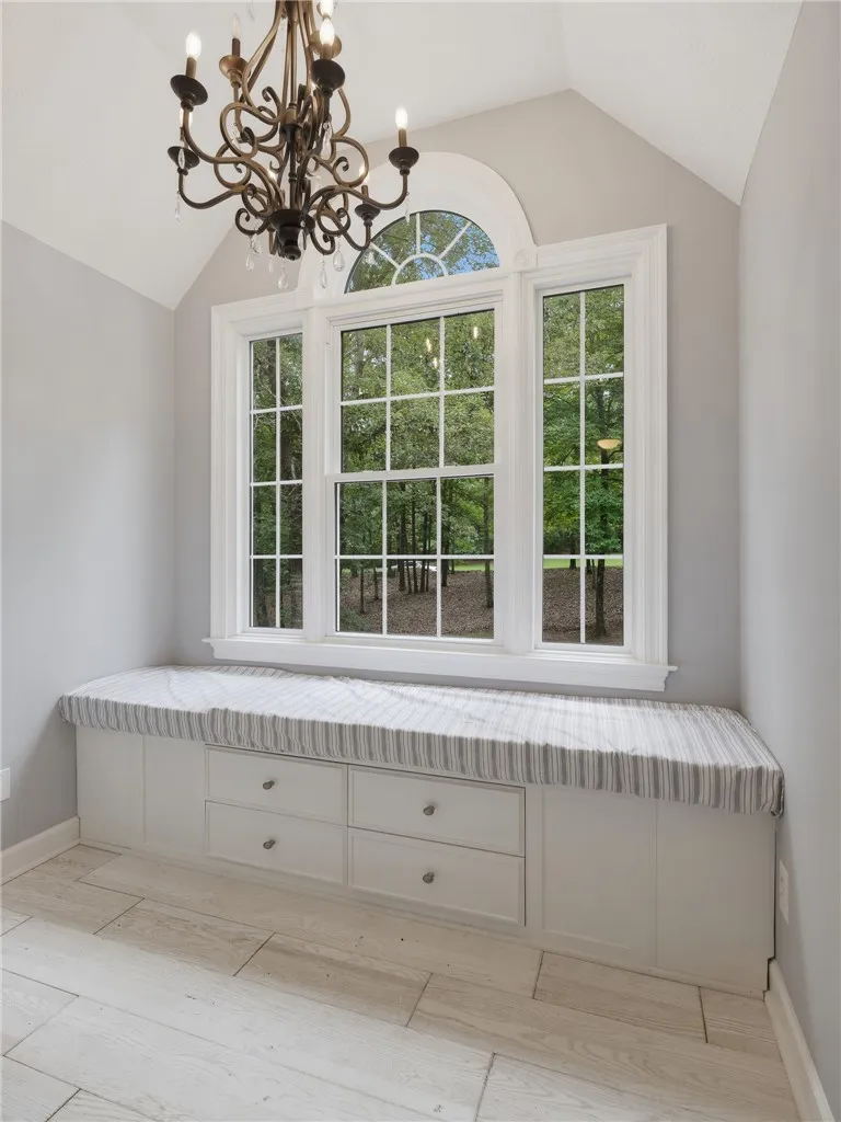 An elegant arched window illuminates this cozy nook featuring a custom built-in bench and plank flooring.