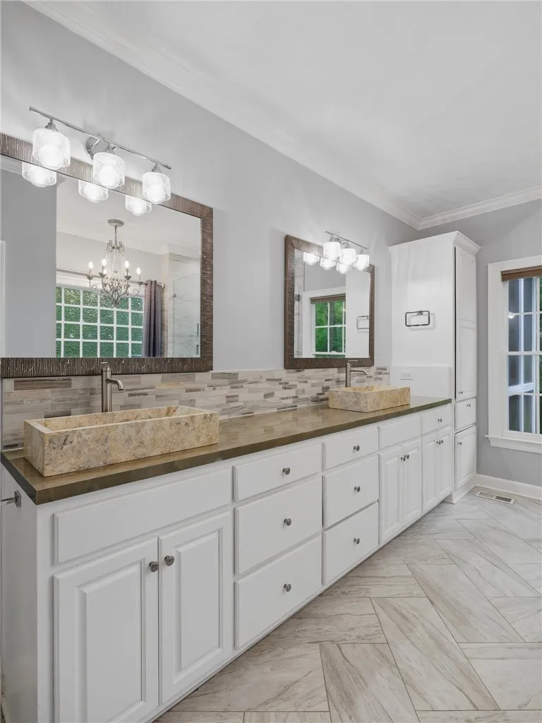 Double stone vessel sinks accent the long vanity in this refreshed bath with tiled floors.