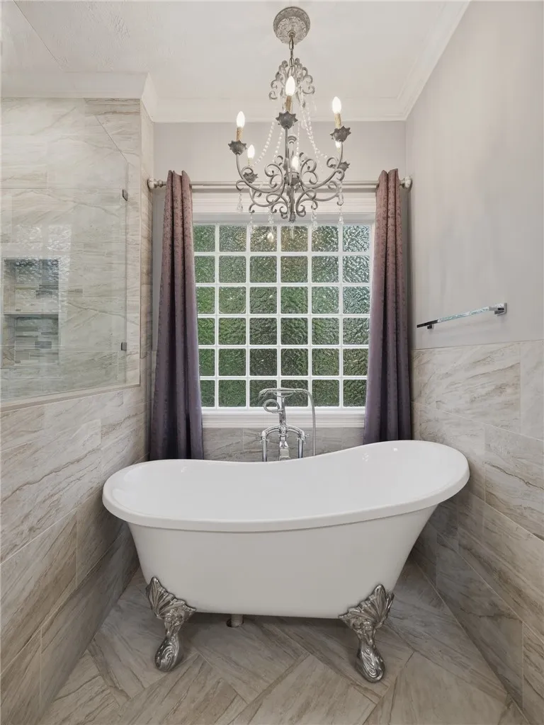 Elegant tilework surrounds a classic clawfoot tub situated beneath a privacy glass window.
