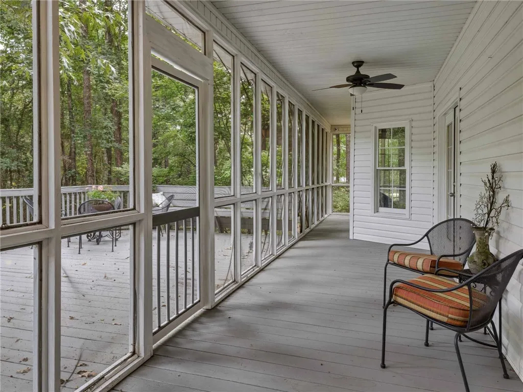 A spacious screened porch opens directly onto a large adjacent deck overlooking dense woods.
