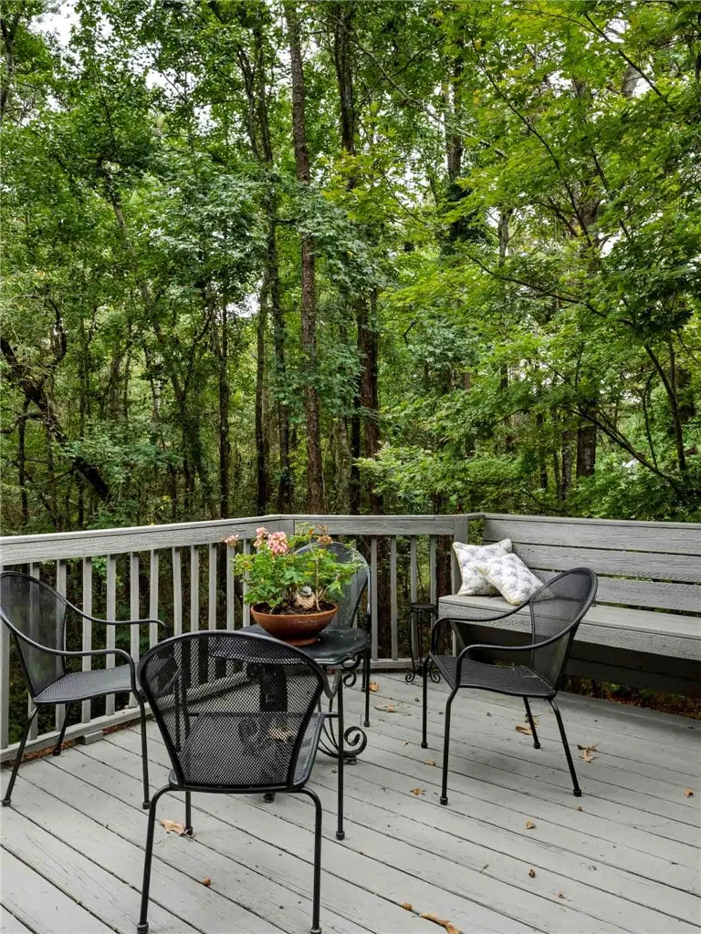 A spacious wooden deck looks out over a dense, serene forest backdrop.