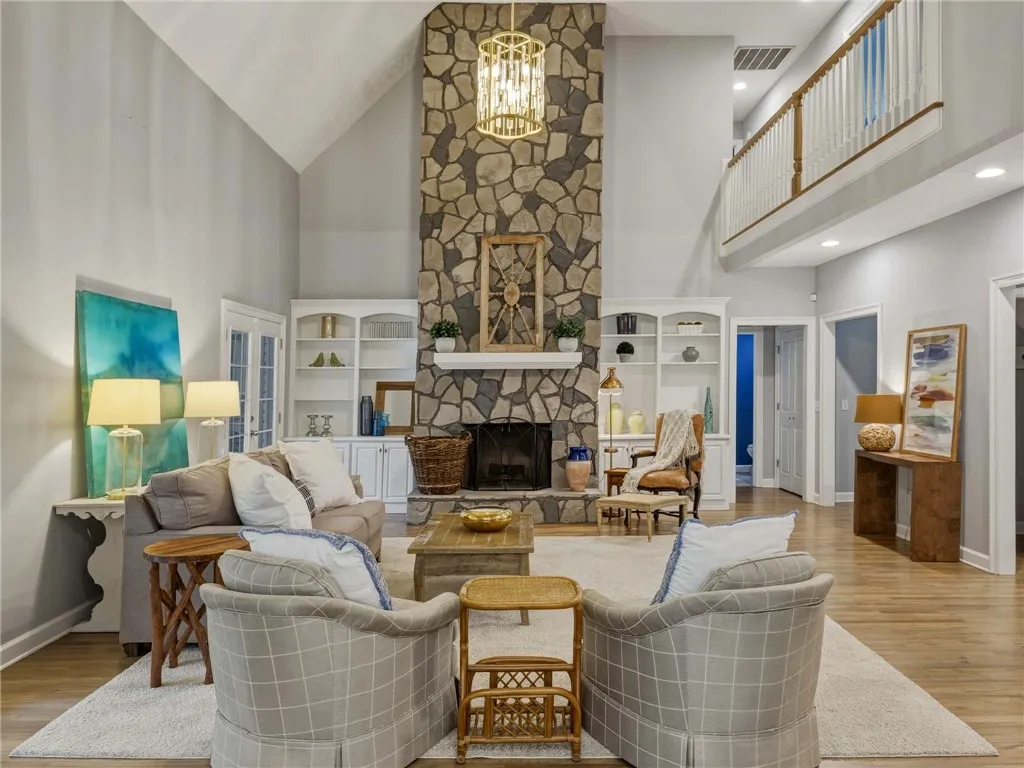 Soaring ceilings and a floor-to-ceiling stone fireplace anchor this light-filled living space.