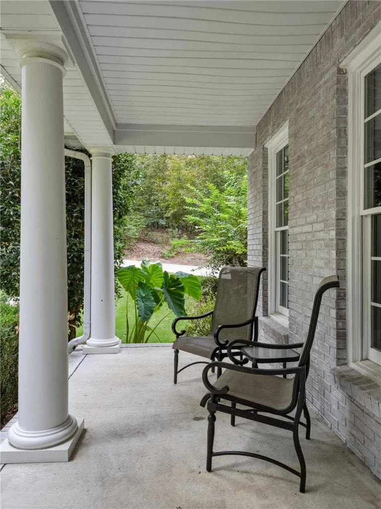 Classical columns support the covered porch framed by textured brick walls.