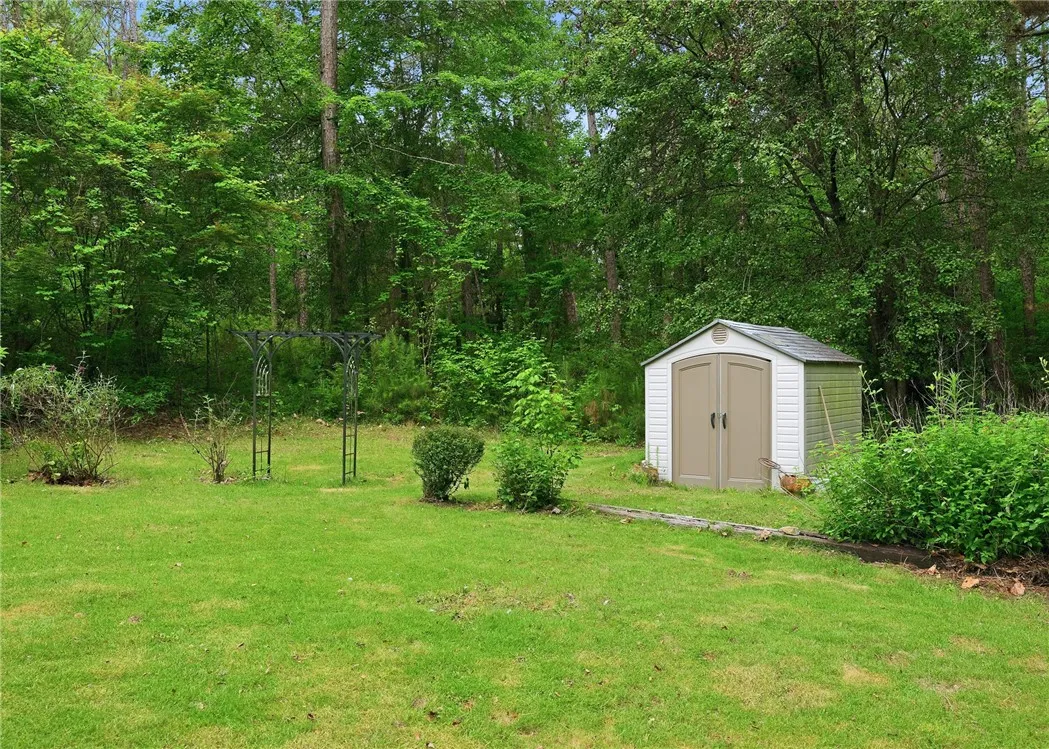 Mature trees frame a private grassy yard complete with a convenient outdoor storage shed.