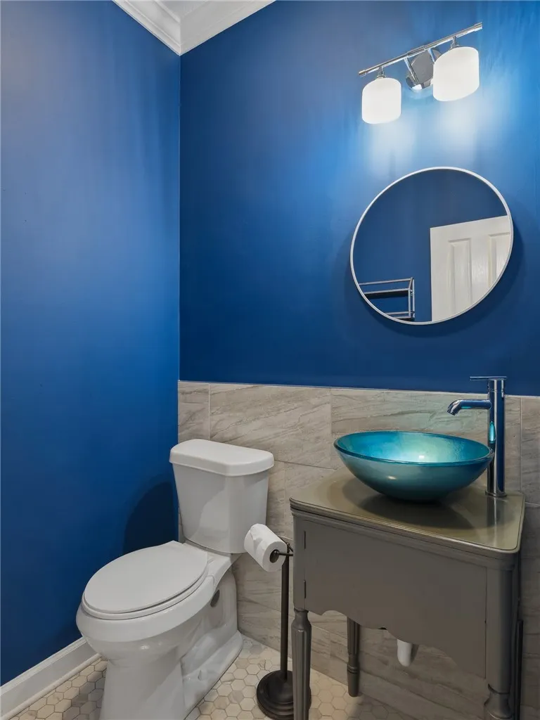 Crown molding and tiled wainscoting highlight this charming powder room.