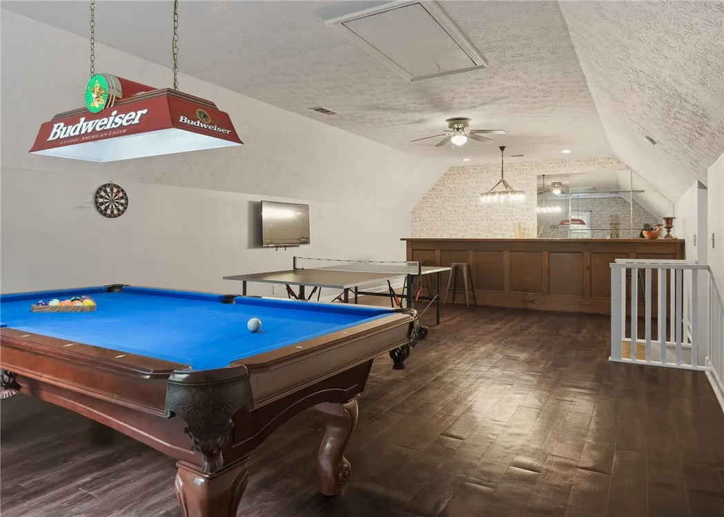 Gleaming hardwood floors and a wooden bar define this spacious upper-level recreation room.