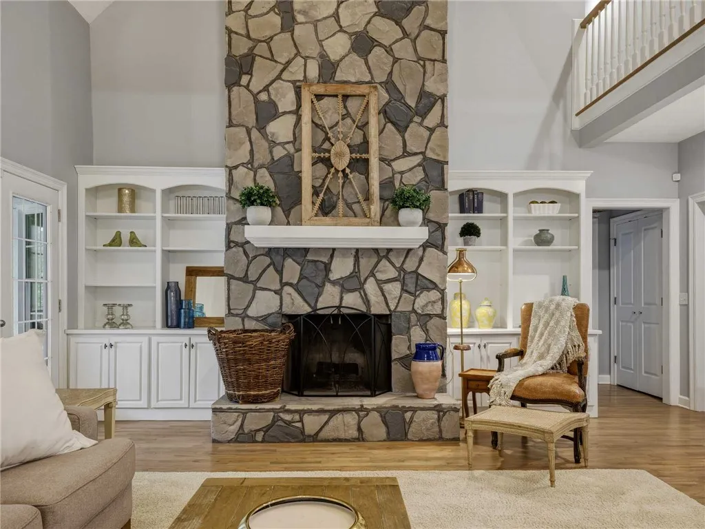 Warm hardwood floors complement a soaring floor-to-ceiling stone fireplace flanked by custom built-ins.
