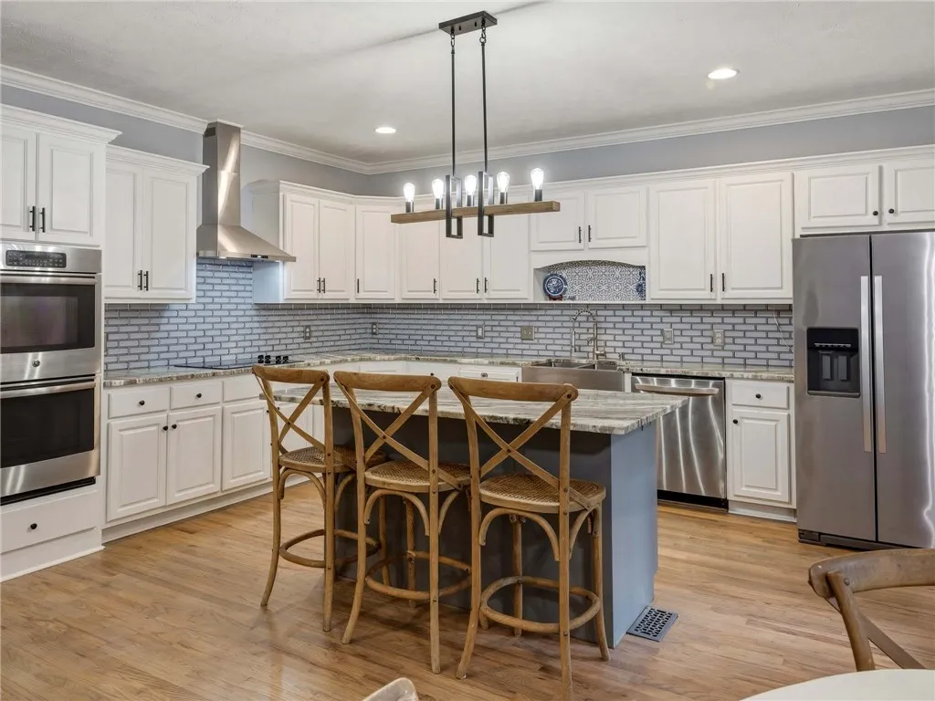 Rich hardwood flooring complements custom white cabinetry and premium stainless steel appliances.