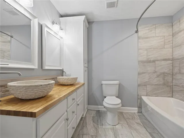 Double vessel sinks and a wood countertop elevate this clean, modern bathroom.