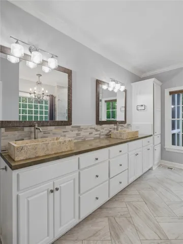 Double stone vessel sinks accent the long vanity in this refreshed bath with tiled floors.