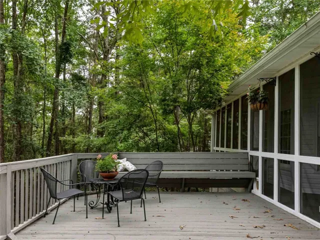 Mature trees frame a spacious wooden deck complete with built-in bench seating.