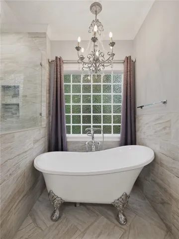 Elegant tilework surrounds a classic clawfoot tub situated beneath a privacy glass window.