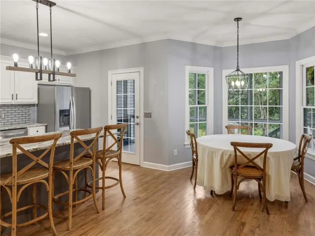 Rich hardwood floors complement the bright breakfast area flowing into a well-appointed kitchen.