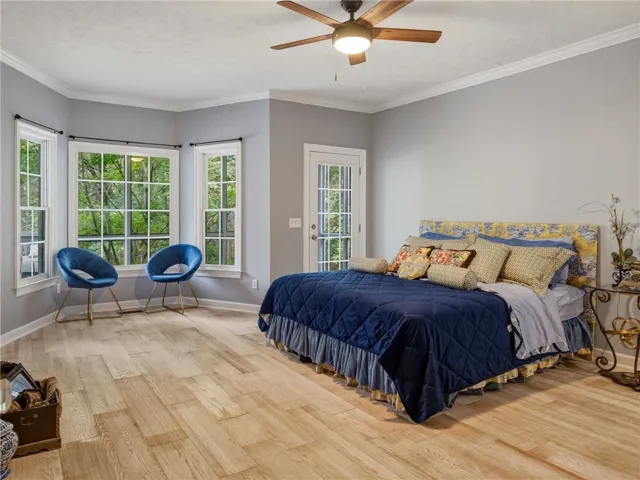 Gleaming wood floors and detailed crown molding enhance this airy bedroom retreat.