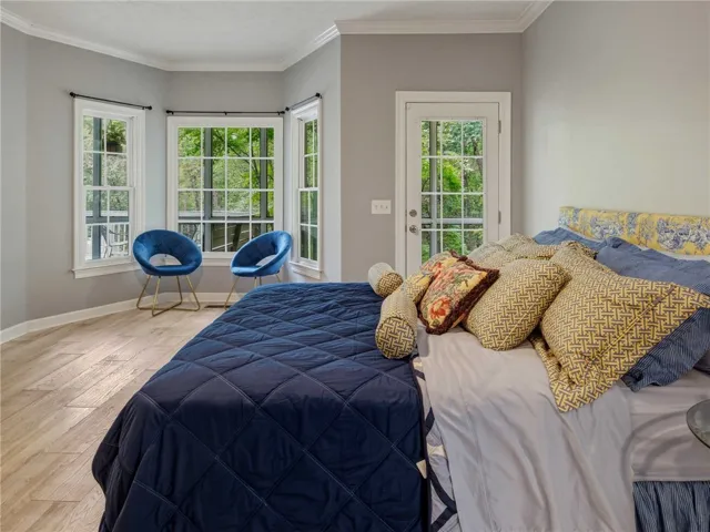 Hardwood floors and a classic bay window enhance this peaceful, light-filled bedroom design.
