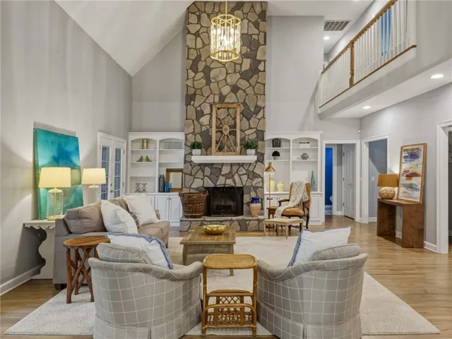 Soaring ceilings and a floor-to-ceiling stone fireplace anchor this light-filled living space.