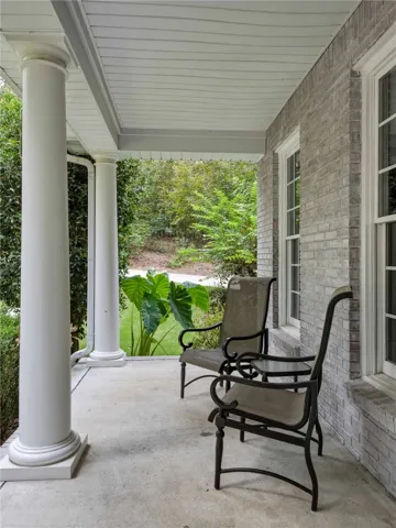 Classical columns support the covered porch framed by textured brick walls.