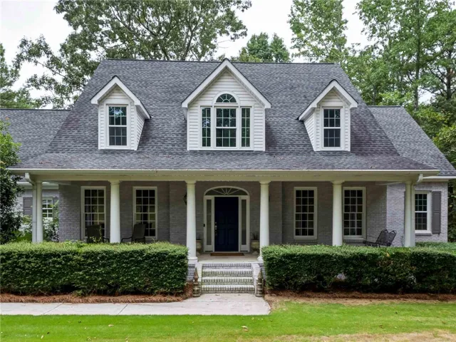 Dormer windows and a covered front porch create a classic, welcoming facade.