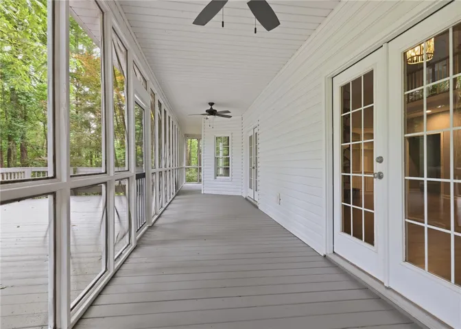 An airy screened porch features classic wood decking and elegant French door access.