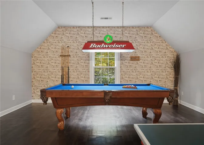 Rich dark wood flooring and a single window define this versatile upper-level recreation room.