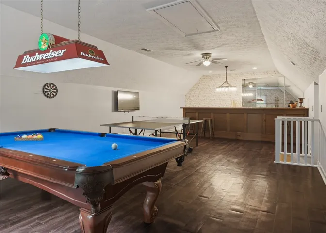 Gleaming hardwood floors and a wooden bar define this spacious upper-level recreation room.