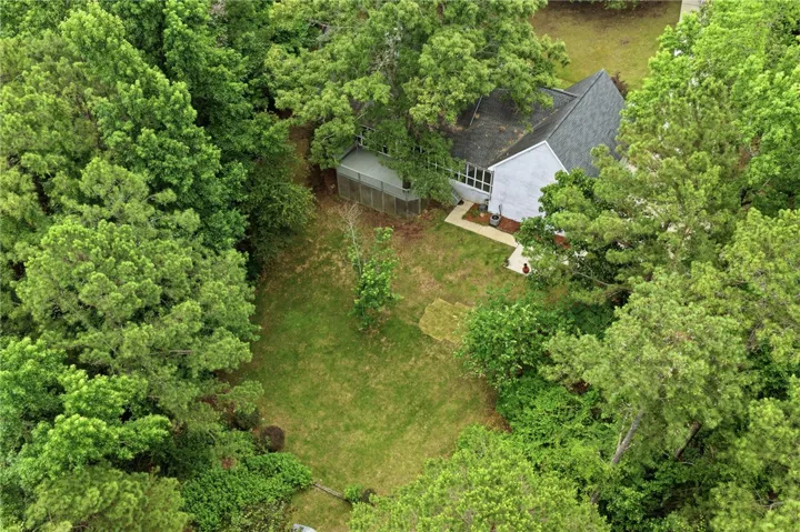 Mature trees frame a private lawn behind this home featuring a raised deck.