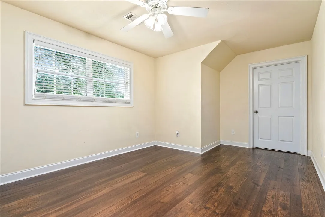 Rich hardwood flooring complements the naturally illuminated, generously sized bedroom.
