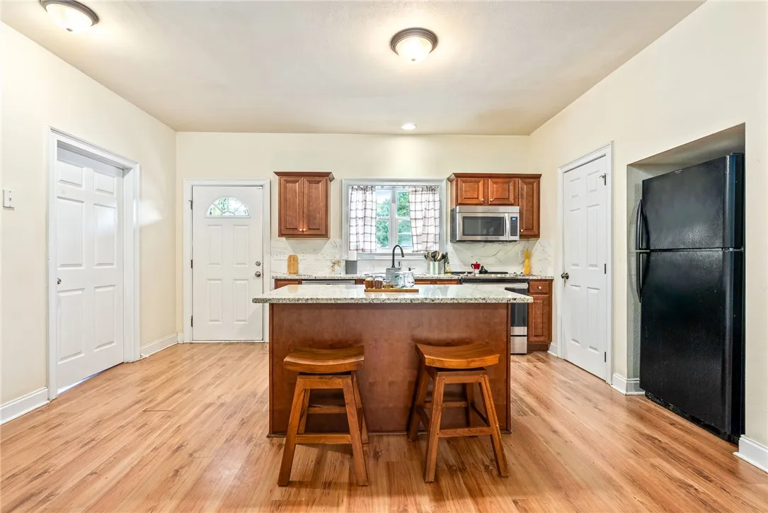 A well-appointed kitchen features a central island, granite counters, and wood flooring.
