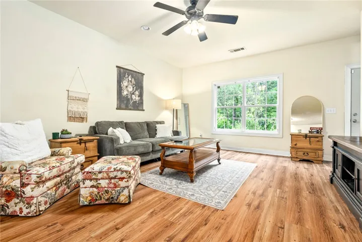 Luminous living area features gleaming hardwood floors and ample natural illumination from a large picture window.