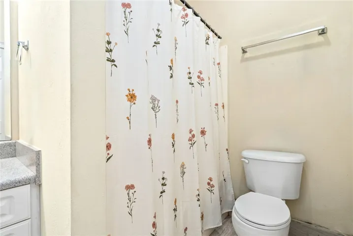 A well-maintained lavatory featuring a floral shower curtain and a white toilet.