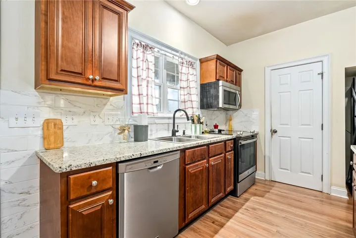 A well-equipped culinary space featuring rich wood cabinetry, durable granite countertops, and stainless steel appliances.
