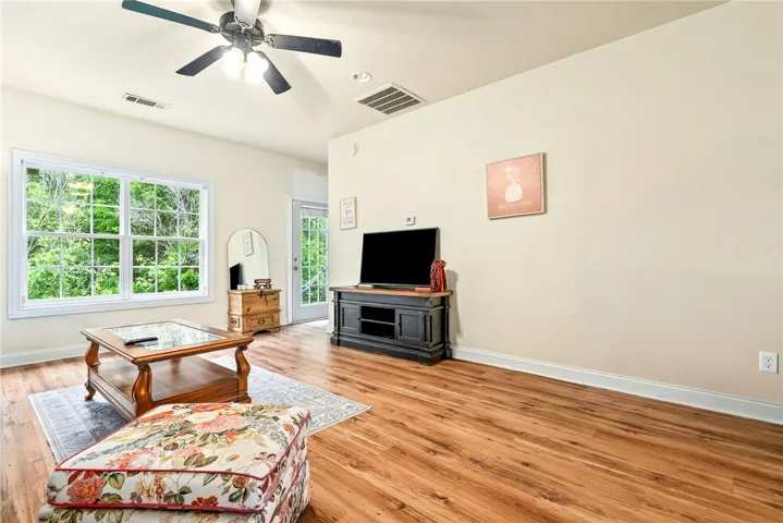 A well-lit living space with wood flooring and verdant outdoor views.